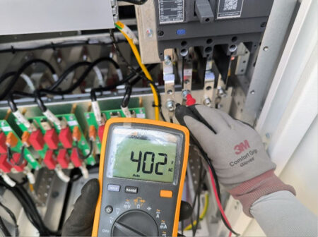 Technician inspecting the cable voltage at a BESS plant.